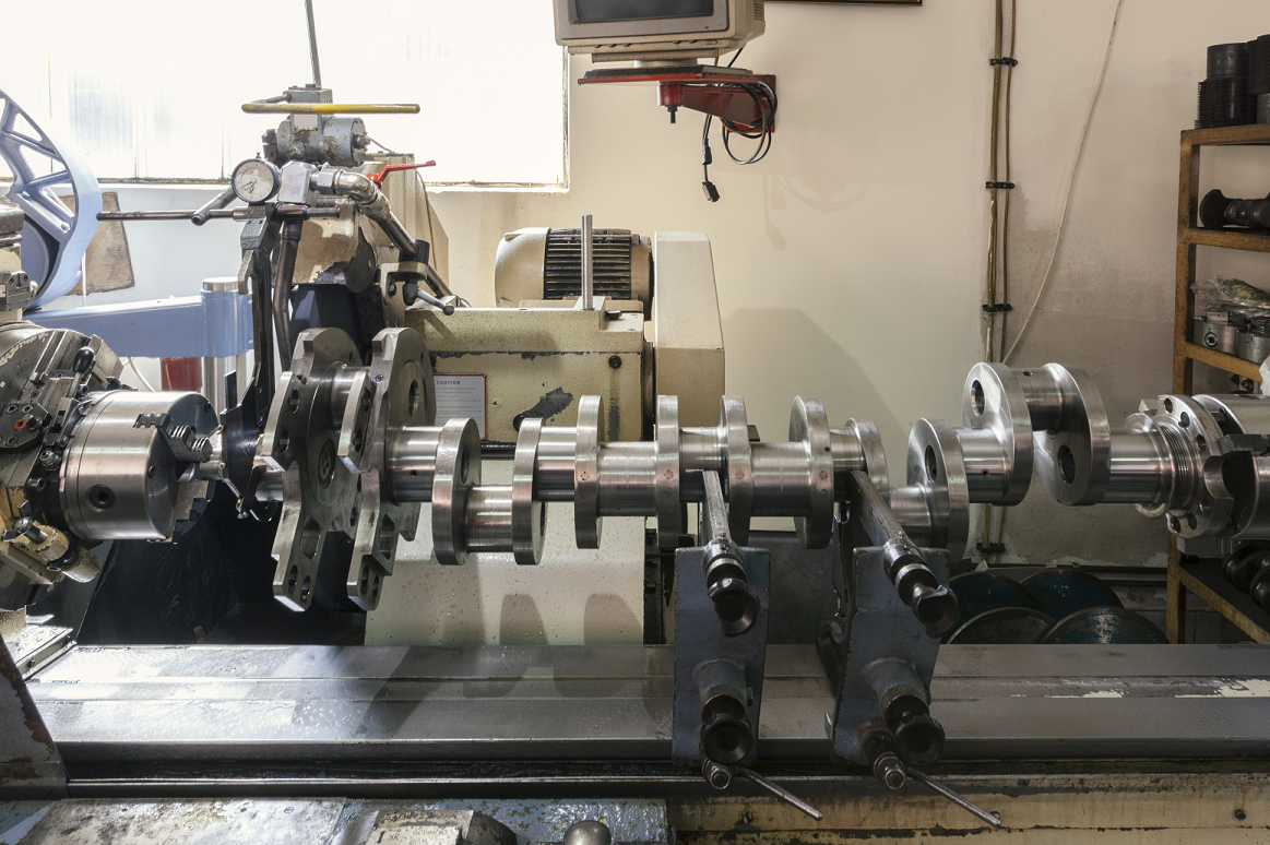 Heavy equipment crankshaft being repaired on a workbench during a major engine rebuild